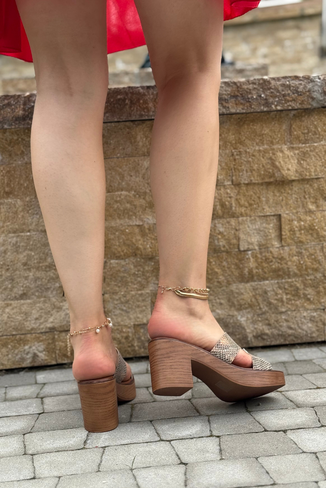 Modne złote klapki z motywem węża na słupku z platformą